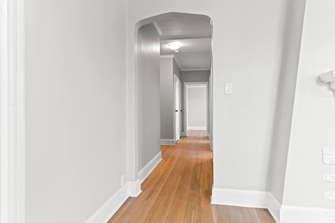 A long hallway with wood floors and white walls.